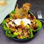 Caesar salad met een gepocheerd eitje en crispy kippenvel