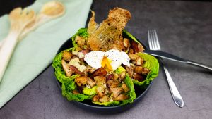 Caesar salad met een gepocheerd eitje en crispy kippenvel